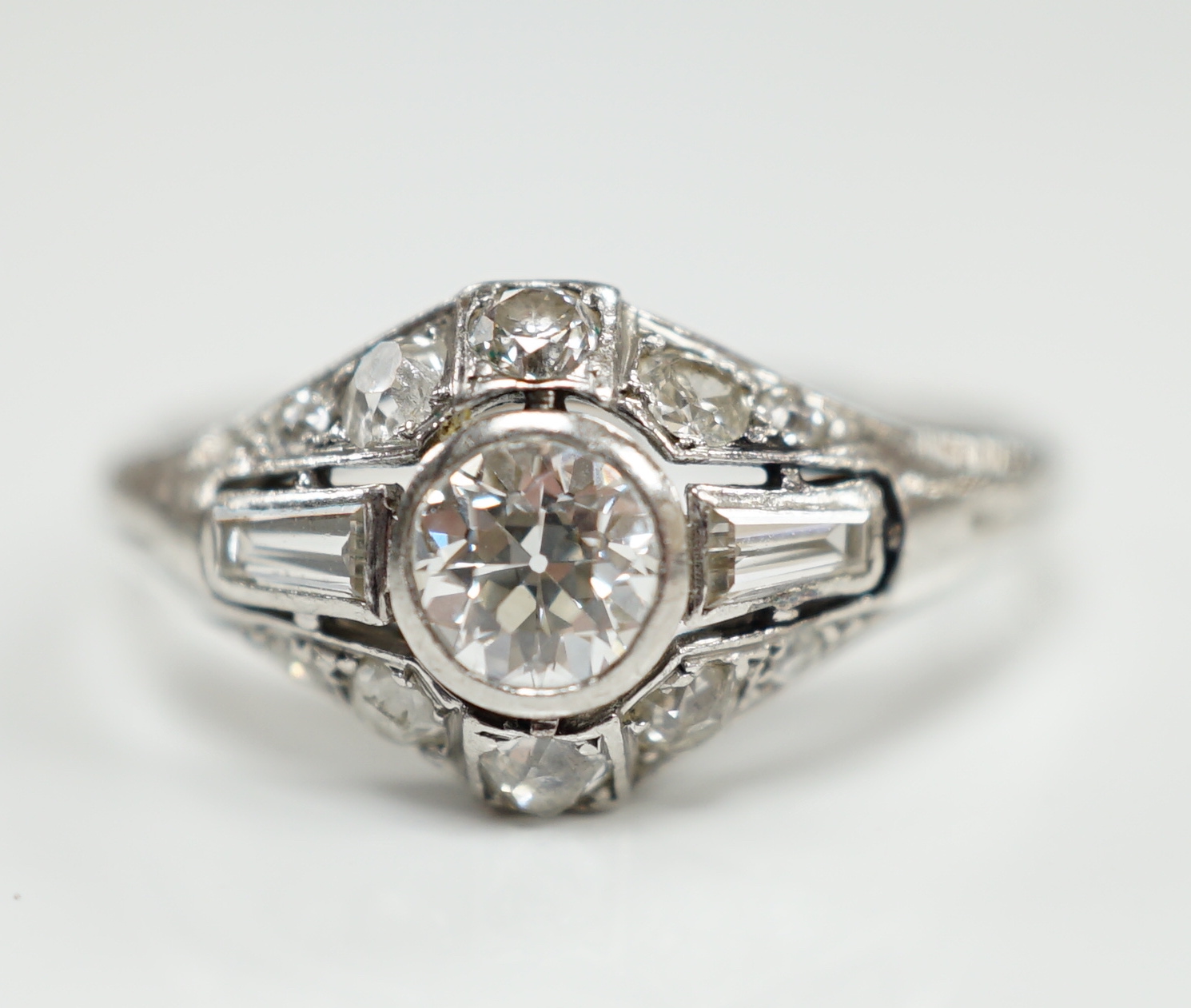 An Art Deco white metal and diamond cluster ring, set with round and trapeze cut stones, size R, gross weight 5 grams.